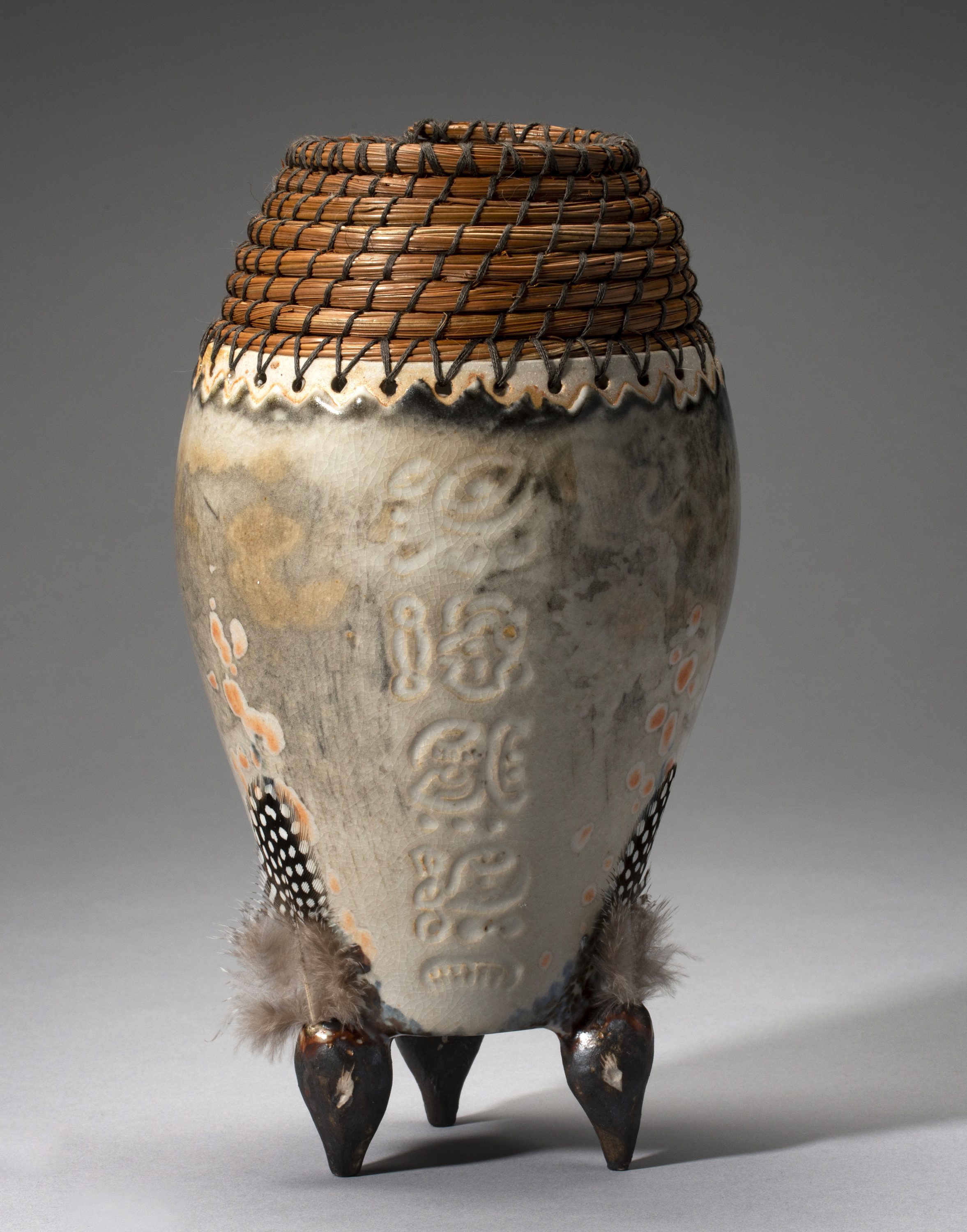 Bird Head Tripod, Stoneware thrown on the wheel with hand sculpted bird heads. Shino glaze, fired in a gas kiln to cone 10 reduction, with woven pine needles and feathers. 6” x 6” x 11”.