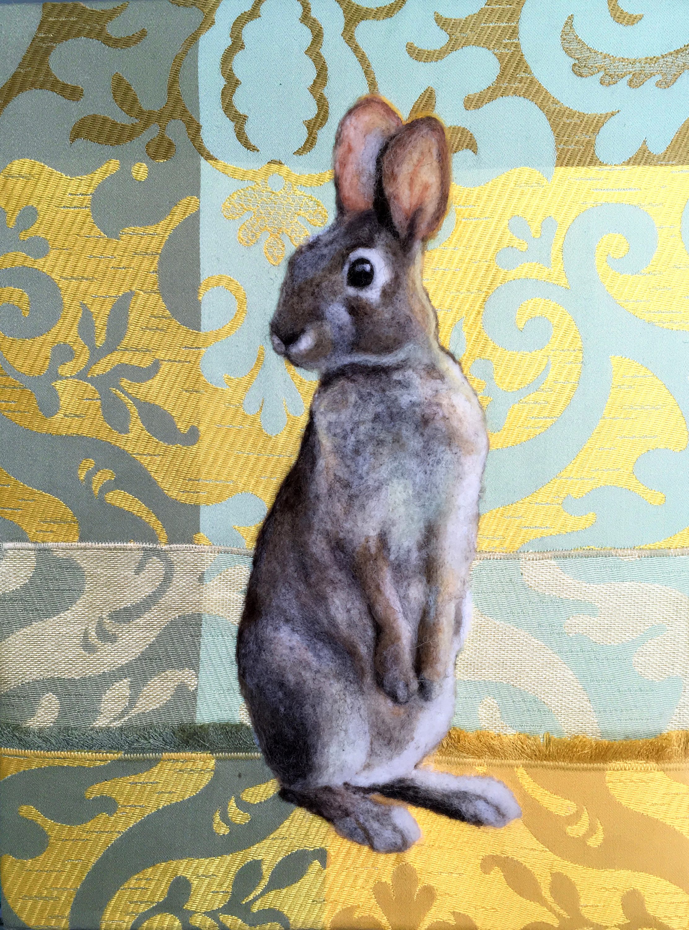 Juliana Boyd creates a whimsical world of work in a technique called needle felting. She takes un-spun wool roving and applies it onto a background fabric with a barbed needle. The felting process takes place as the wool is repeatedly punched down by the needle, causing the fibers to compact together. She writes, "The animals and birds that I coax out of the woolen “fluff” have a dimensional realism achieved through the sculptural qualities of my felting, and the complex blending of colors in the wool that I choose." "Sunbeam Bunny": 2D needle felting on textile background. 9" x 12"